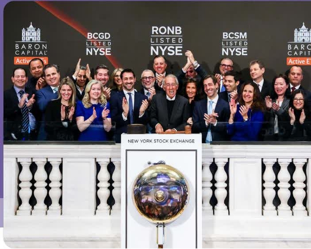 A group photo of the Baron Capital team and NYSE officials at a bell-ringing ceremony. Banners in the background list 'BARON CAPITAL Active ETFs', 'BCGD LISTED NYSE', 'RONB LISTED NYSE', and 'BCSM LISTED NYSE'. A bell is visible in the foreground.